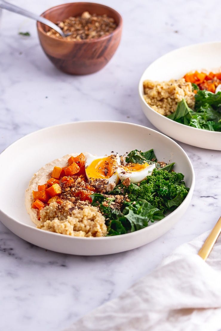 Breakfast bowls with a wooden bowl of dukkah on a marble surface