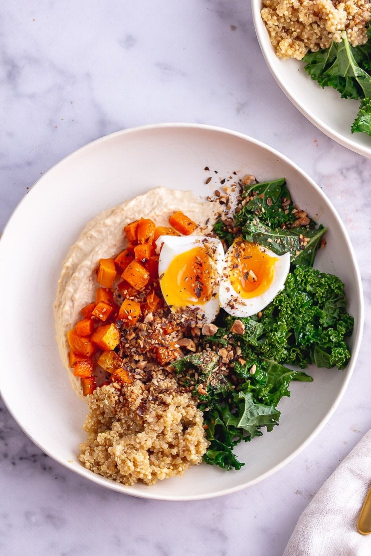 Overhead shot of vegetarian breakfast bowl with hummus on a marble surface