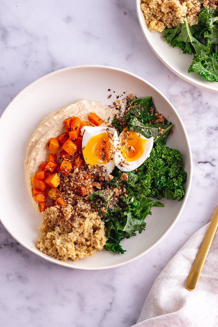 Overhead shot of breakfast bowl with a gold fork on a marble background