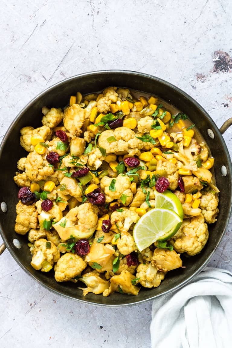 Overhead shot of one pan cauliflower curry on a grey background for vegan comfort food round up