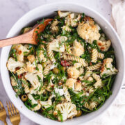 Overhead shot of roasted cauliflower pasta with a wooden spoon on a marble background