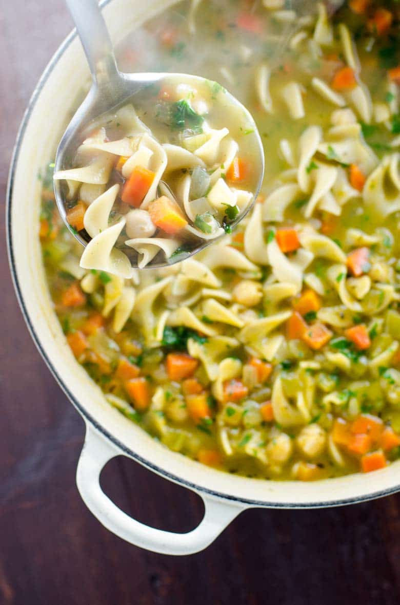 Overhead shot of chickpea noodle soup in a pot with a ladle from Umami Girl for vegan comfort food round up