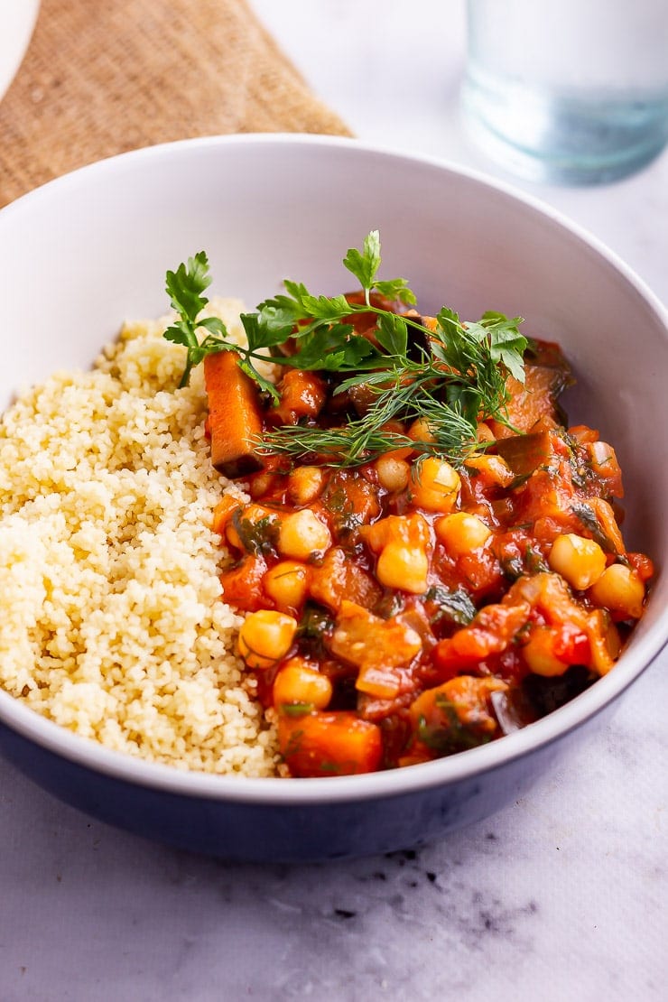 Side on shot of harissa chickpea stew with couscous in a blue bowl