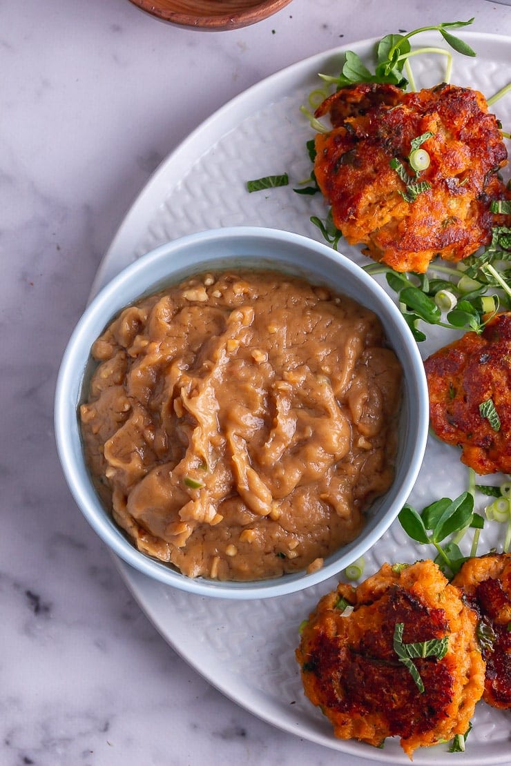 Overhead shot of peanut sauce in a blue bowl with Thai fish cakes