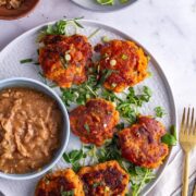 Overhead shot of Thai fish cakes with peantu sauce on a grey plate on a marble surface