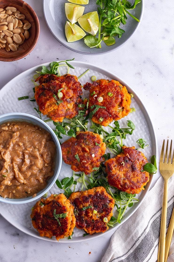 Overhead shot of Thai fish cakes with peantu sauce on a grey plate on a marble surface