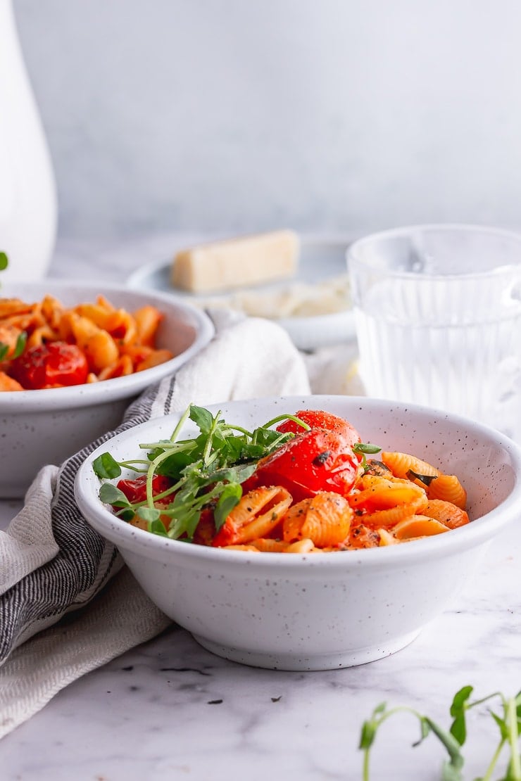 Side on shot of tomato pasta in white bowls on a marble background