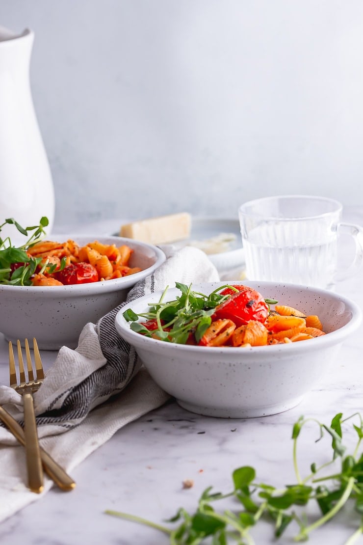 Side on shot of tomato pasta in white bowls on a marble background