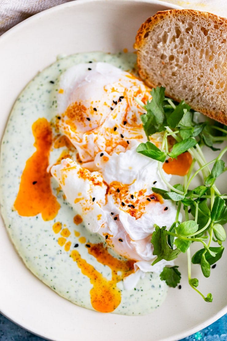 Close up of Turkish eggs in a white bowl with bread