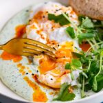 Turkish eggs with a fork breaking the yolk