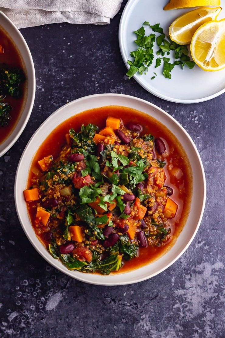 Overhead shot of vegan stew with lemon and herbs on a dark background