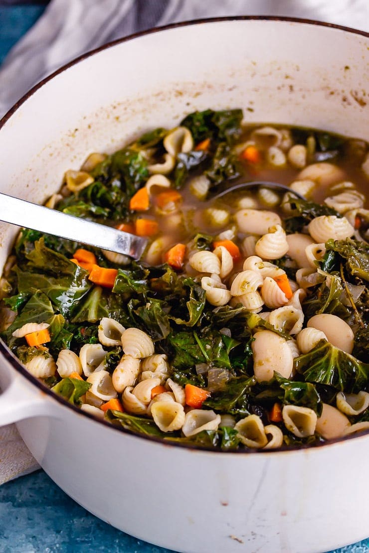 White pot of veggie pesto pasta soup with a ladle