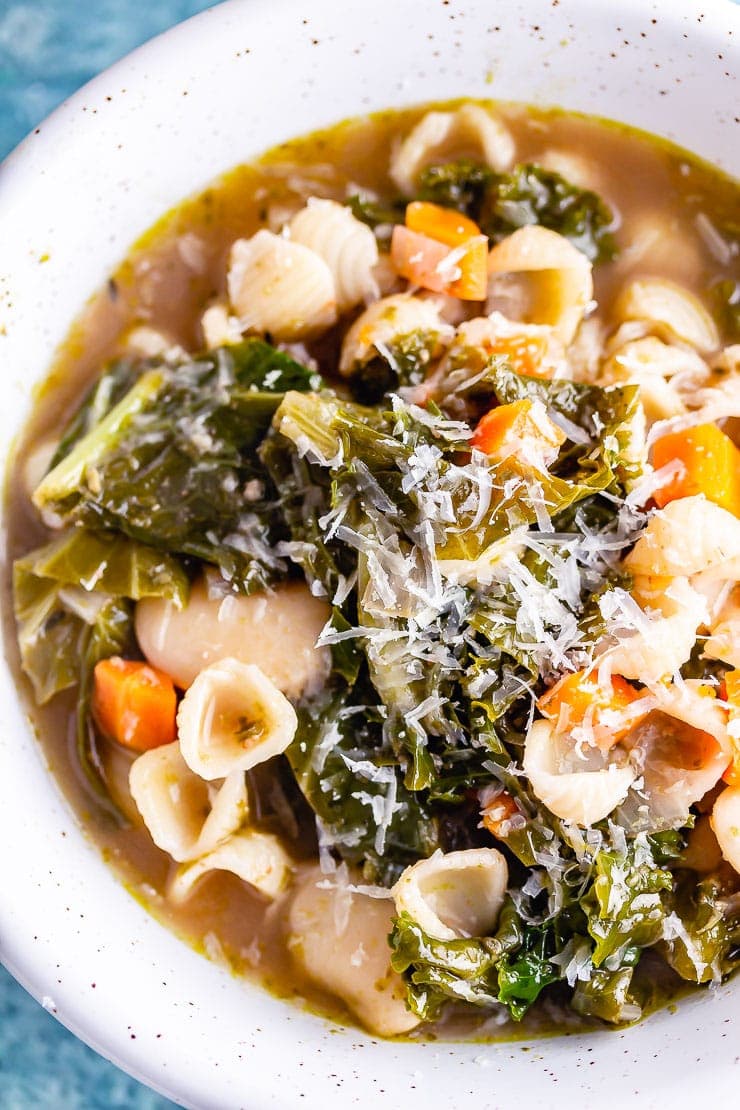 Close up shot of veggie pesto pasta soup in a white bowl