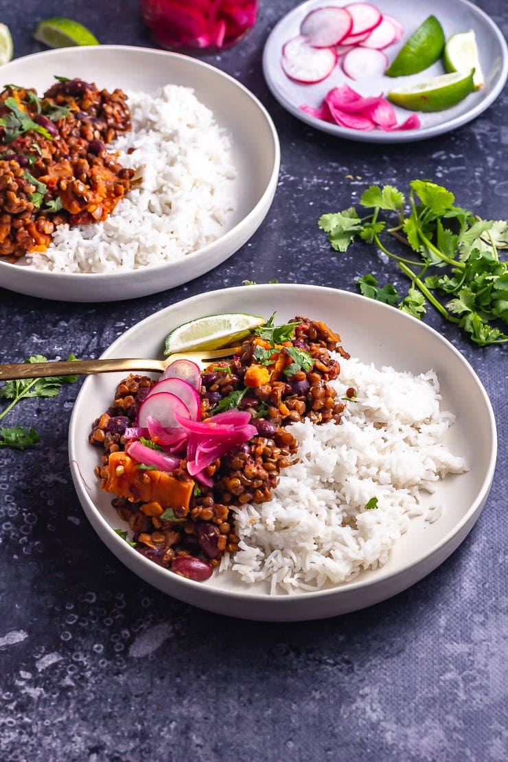 Side on shot of veggie chilli with toppings and rice in a white bowl