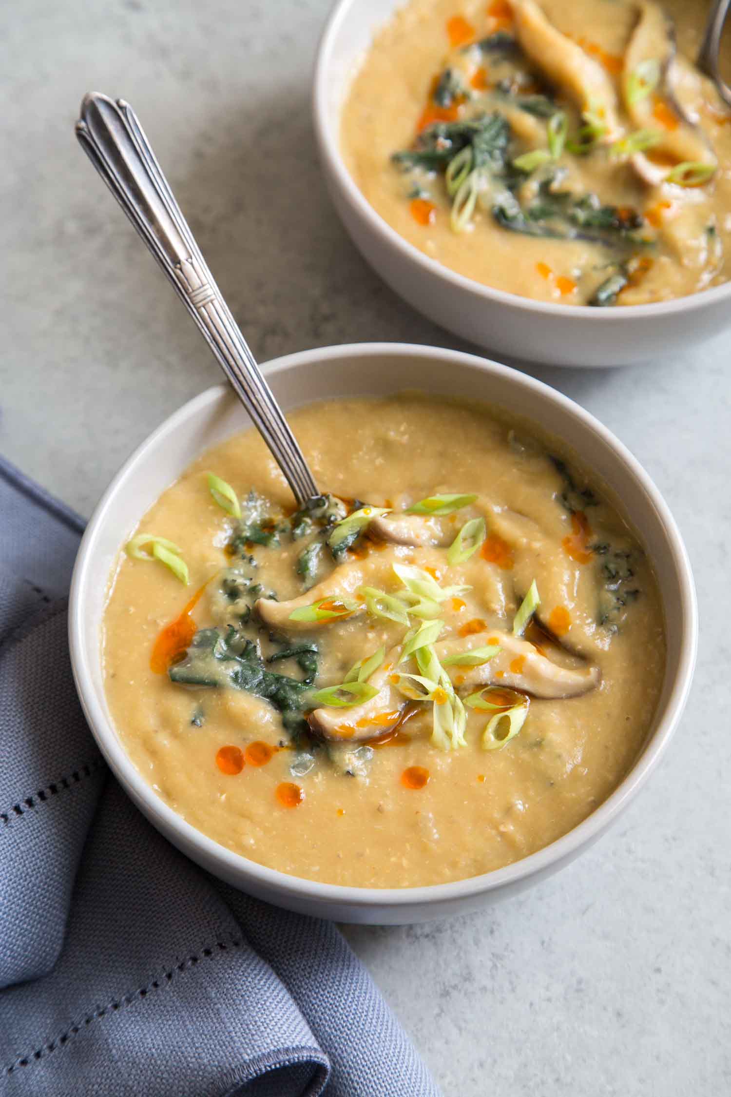 Bowl of miso red lentil soup with a spoon on a light background for vegan comfort food round up