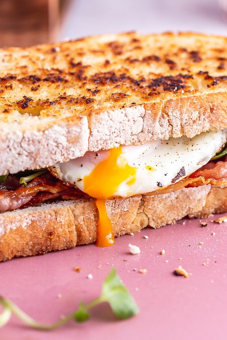 Close up of fried egg dripping yolk from a sandwich