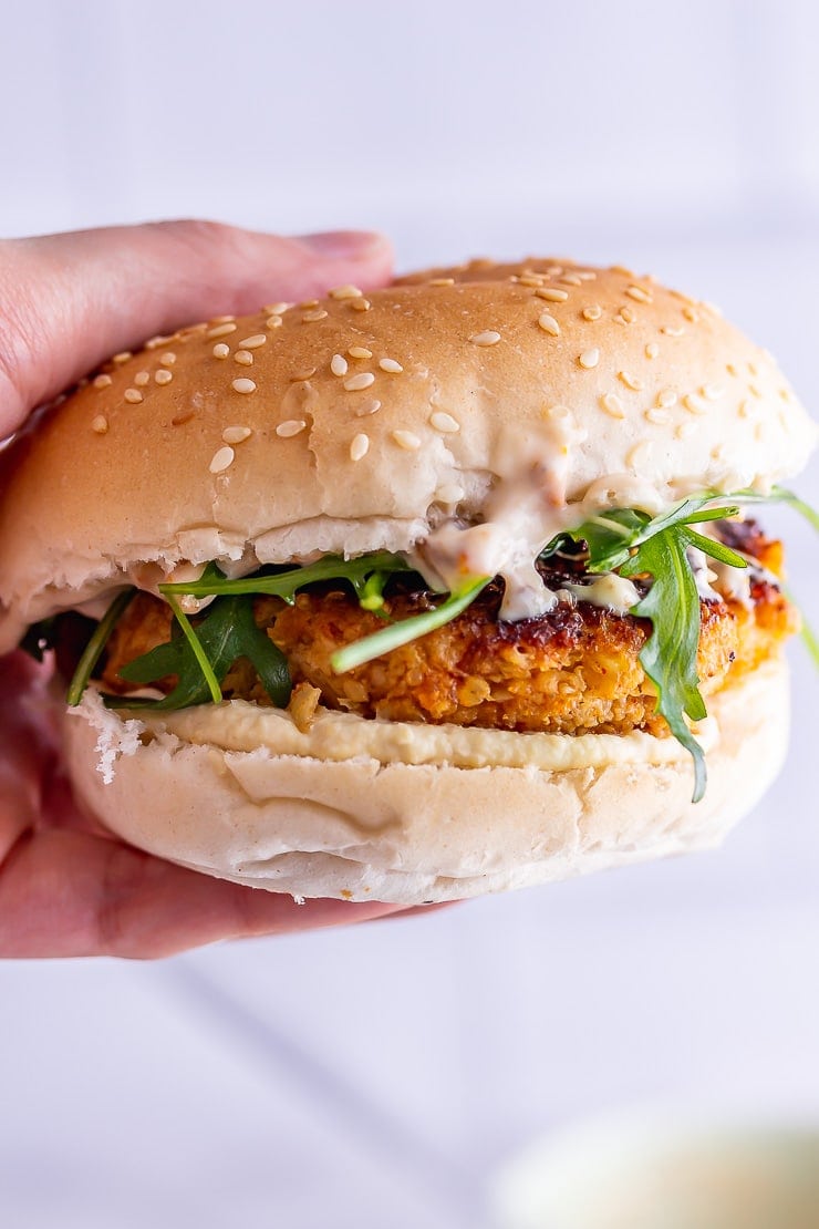 Hand holding one of the best veggie burgers with rocket 