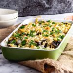 Green baking dish of mushroom pasta bake on a hessian mat over a marble surface