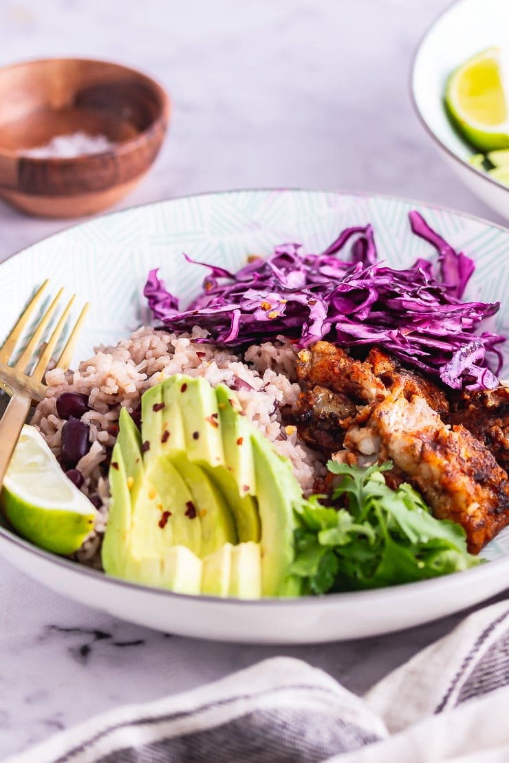 Side on shot of fish taco bowl with avocado and lime