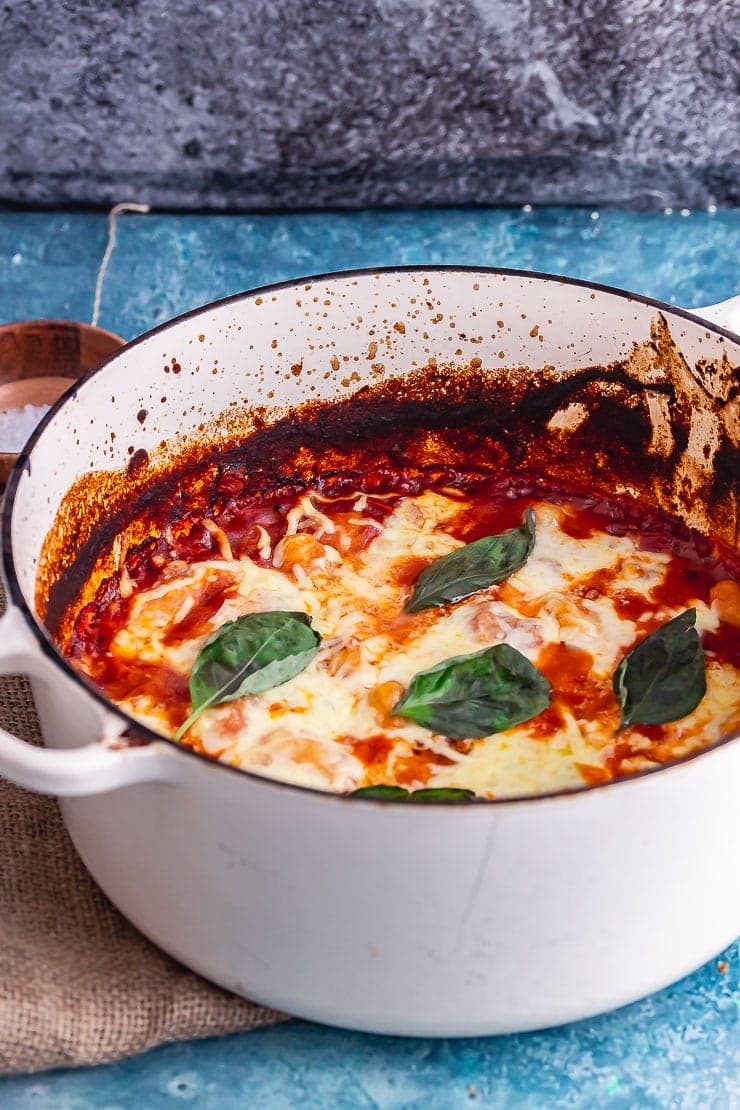 White pot of one pot gnocchi bake topped with basil on a brown mat