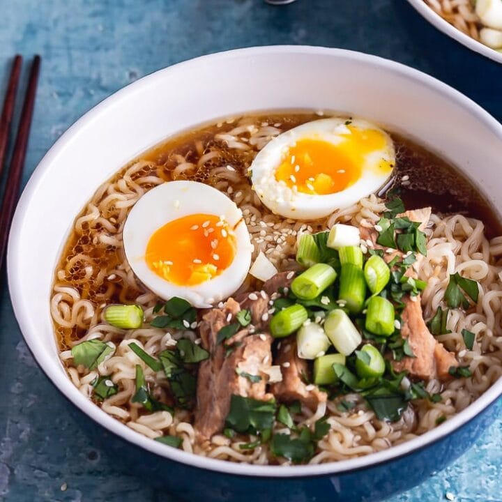 Blue bowl of pork ramen with toppings on a blue background