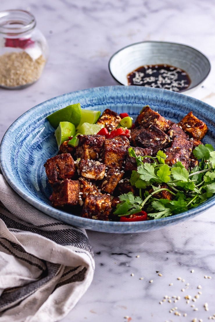 Blue bowl of salt and pepper tofu on a marble background with soy sauce