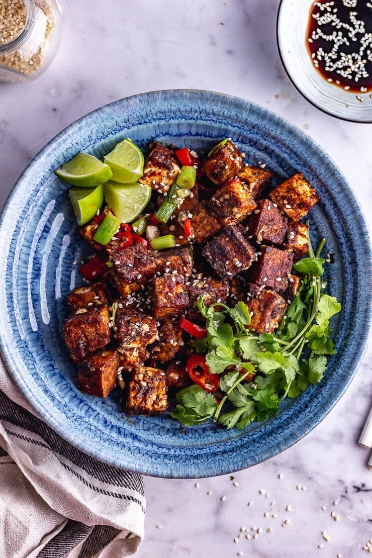 Overhead shot of salt and pepper tofu in a blue bowl with toppings