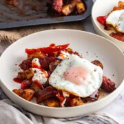 White bowl of veggie sausage bake with a fried egg on top