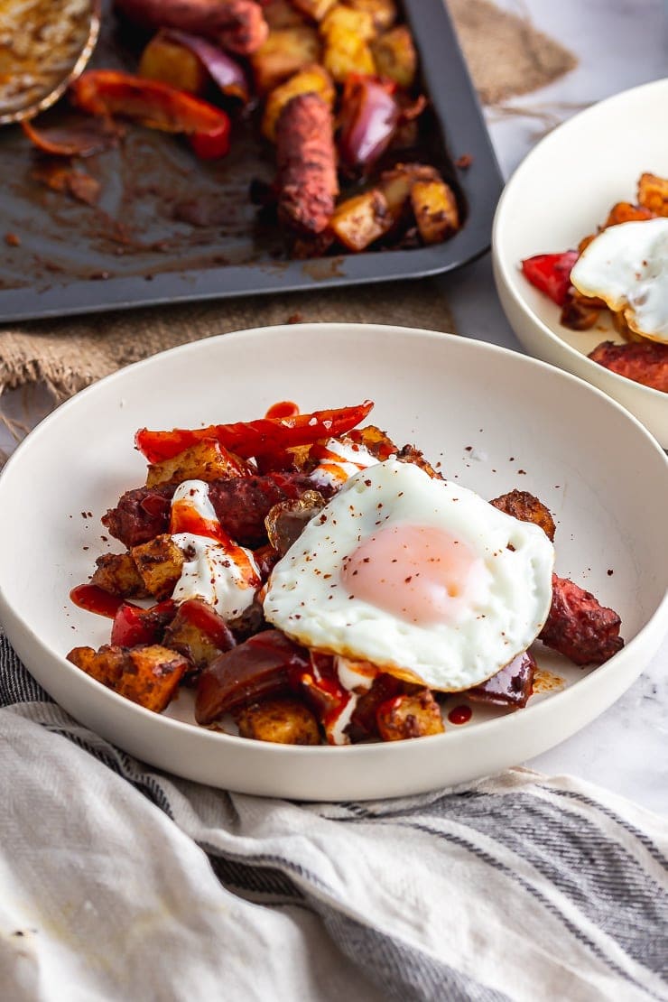 White bowl of veggie sausage bake with a fried egg on top