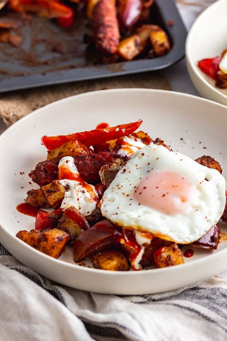 White bowl of veggie sausage bake topped with a fried egg