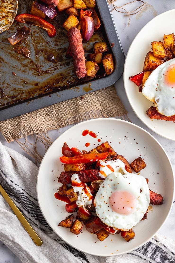 Two bowls of veggie sausage bake with a tray on a cloth