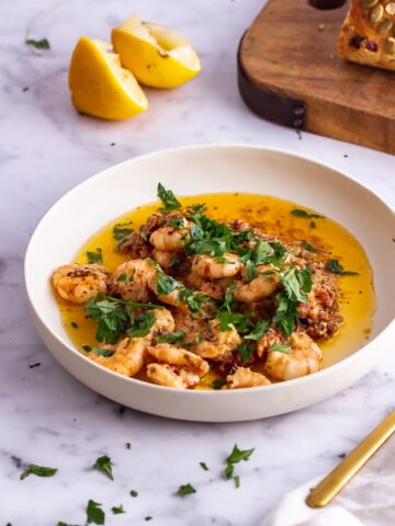 White bowl of chilli prawns on a marble background