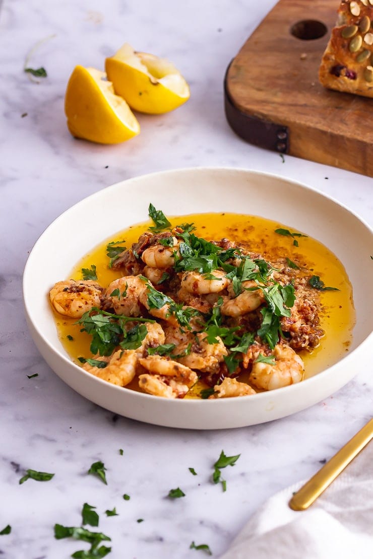 White bowl of chilli prawns on a marble background 