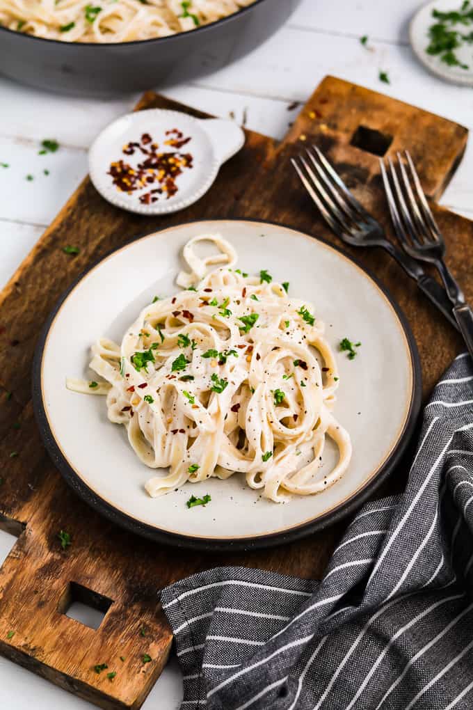 Vegan alfredo sauce pasta on a wooden board