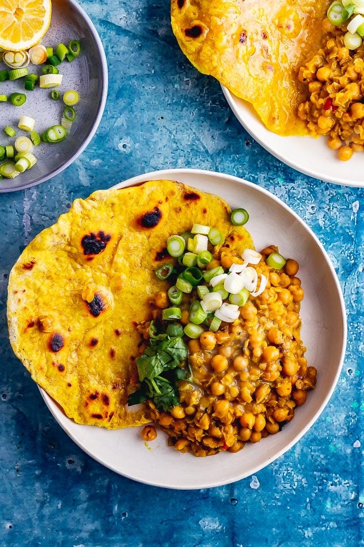 Overhead shot of a white bowl of chickpea curry with spring onions