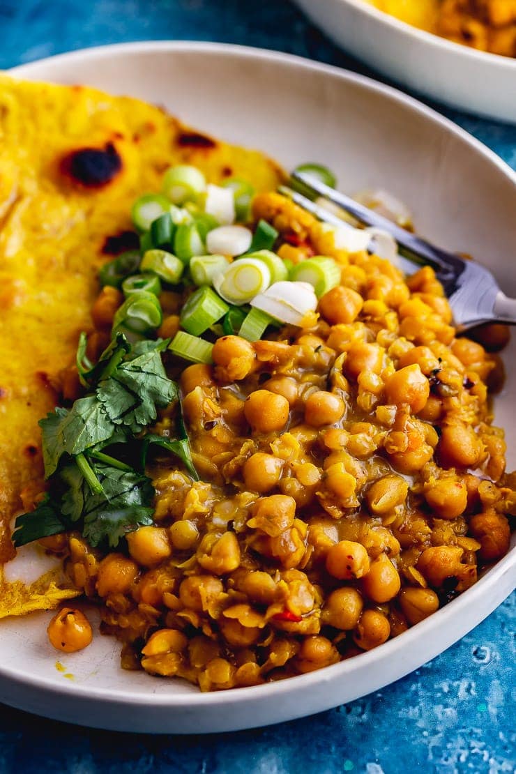 Close up of chickpea curry with spring onions and roti