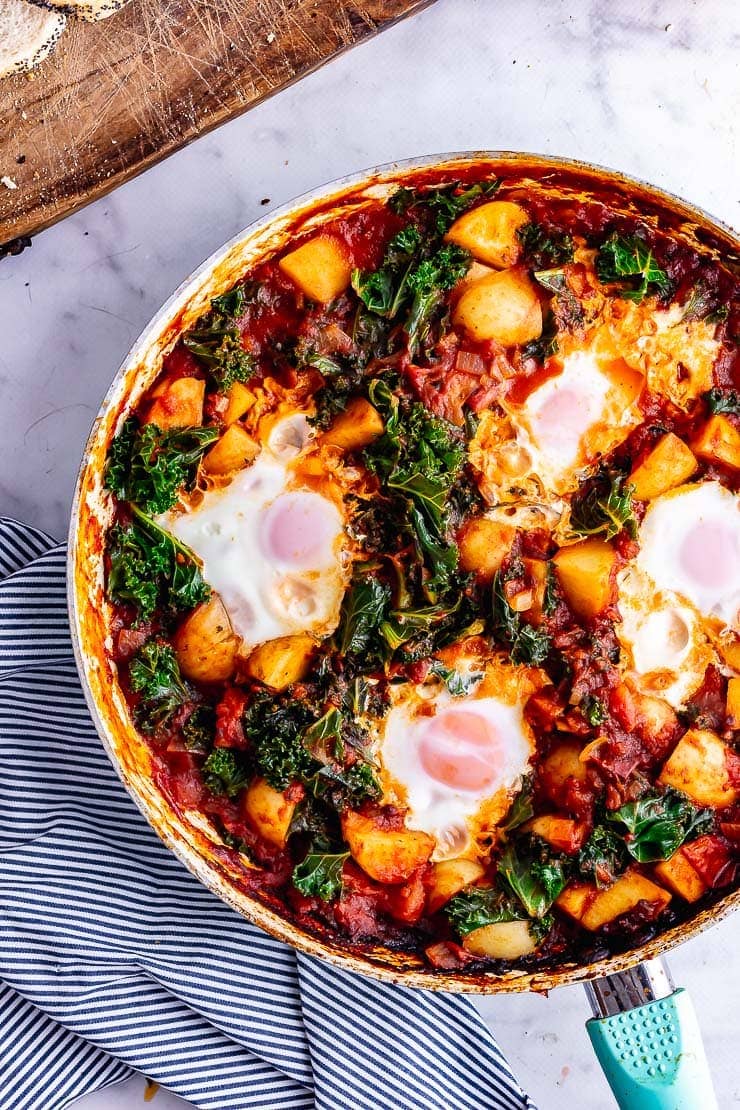 Overhead shot of chipotle eggs and potatoes with kale on a marble surface