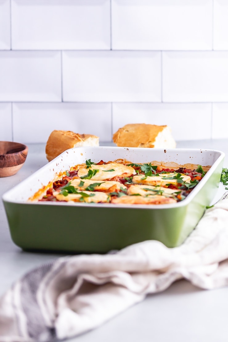 Side on shot of halloumi and kale bake with bread in the background