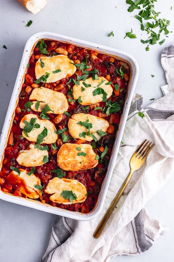 Overhead shot of halloumi bake on a grey background with a gold fork