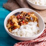 White bowl of vegetable curry with a patterned cloth