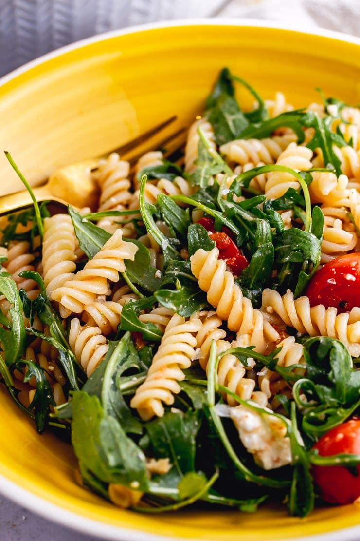 Close up of roasted tomato pasta salad in a yellow bowl