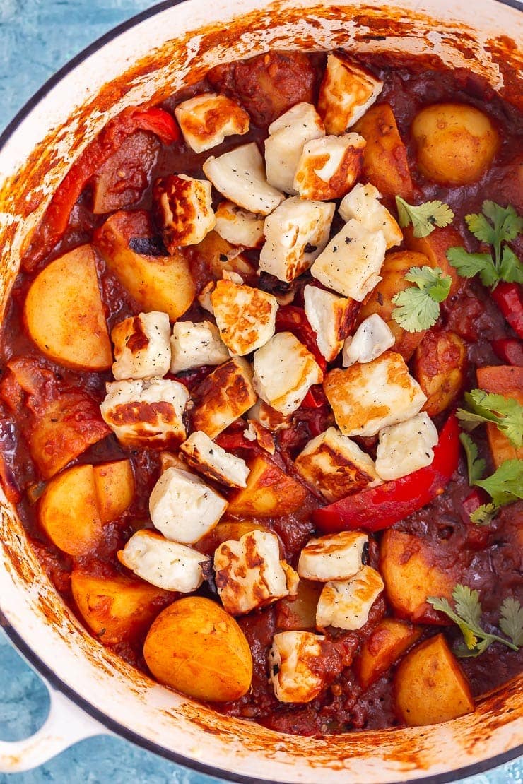 Overhead shot of spicy halloumi curry with potato in a white pot