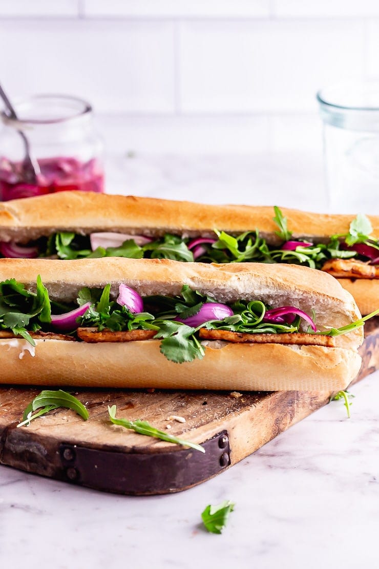 Side on photo of tofu sandwich with pickled onions and rocket