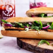 Side on photo of tofu sandwich with pickled onions and rocket