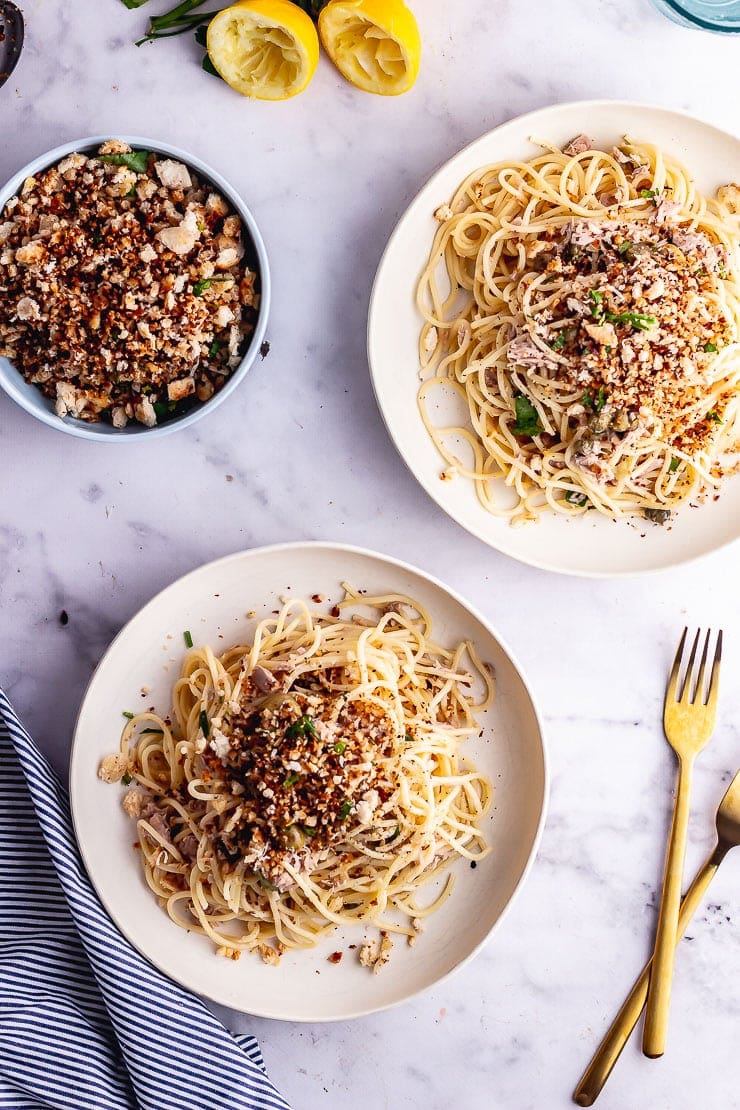 Overhead shot of two bowls of tuna pasta with gold forks