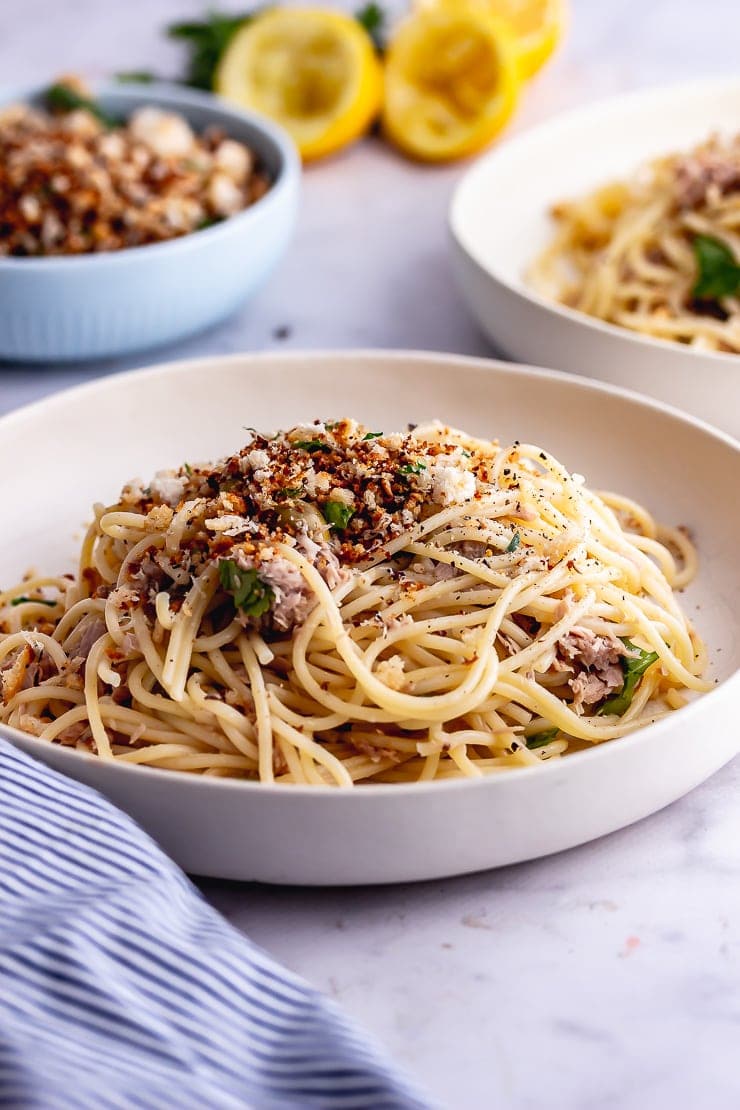 White bowl of tuna pasta with a striped cloth