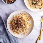 White bowl of tuna pasta with a striped cloth