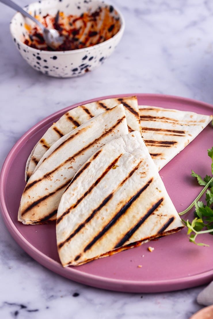 Vegetarian quesadilla on a pink plate with coriander and chipotle paste