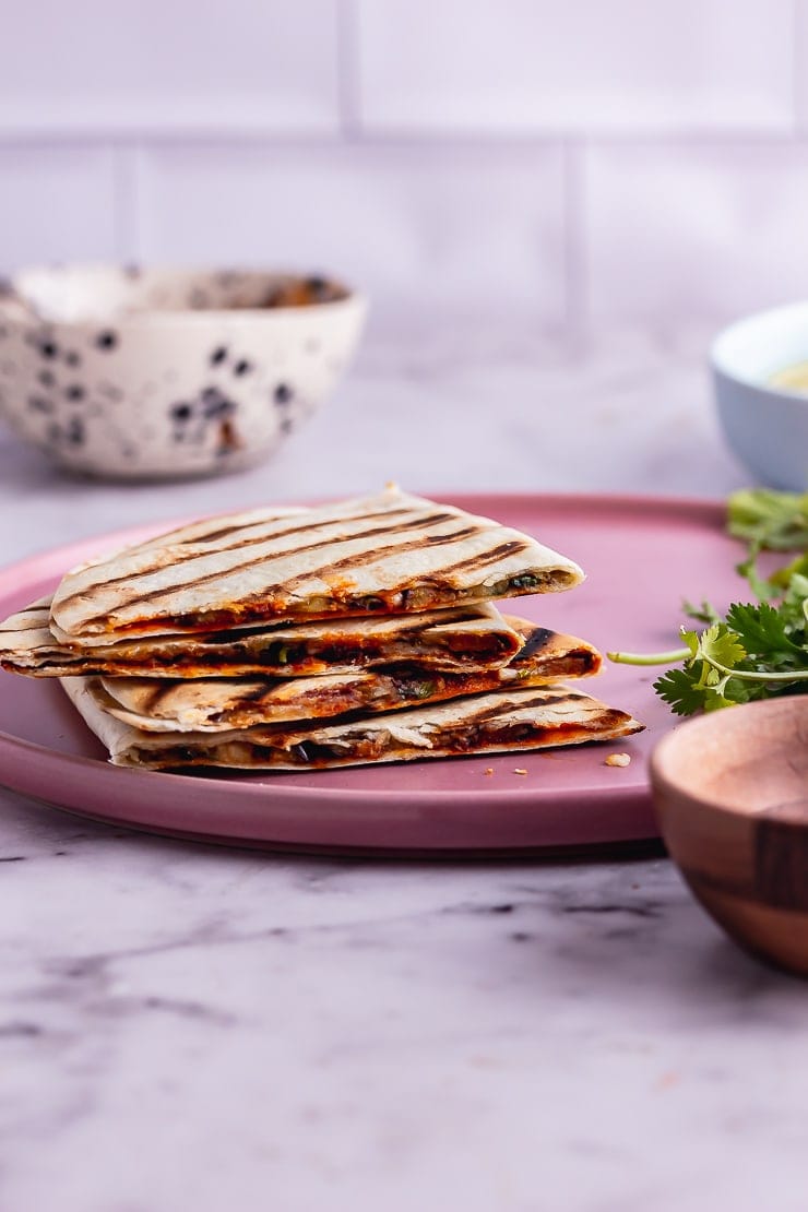 Side on shot of a vegetarian quesadilla stacked up on a pink plate