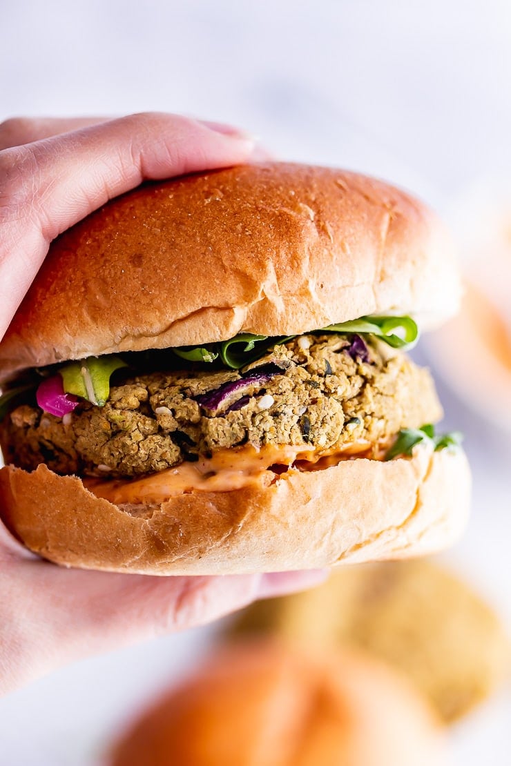 Hand holding a falafel burger in a burger bun